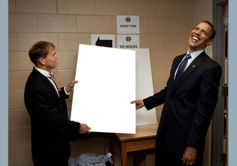 Obama laughing while holding a poster 