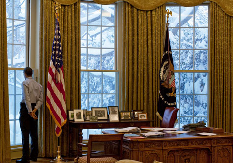 Obama looks at snow outside the window of the Oval Office 