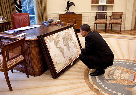 Obama studies world map in Oval Office